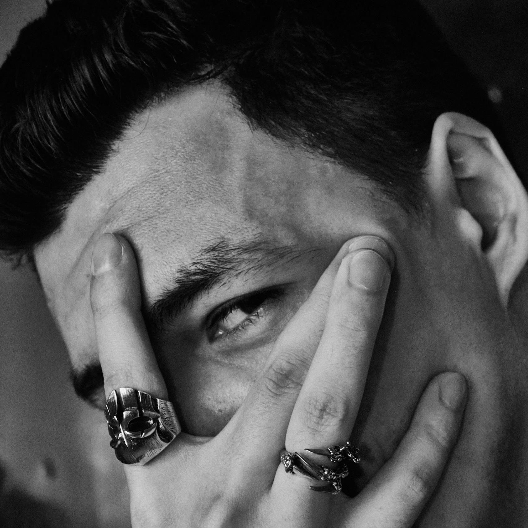 Close-up black and white portrait of a man with rings covering his face